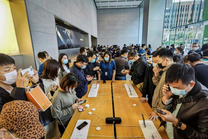 People try out iPhone 12 mobile phones at an Apple store in Shanghai
