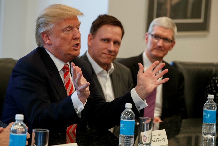 Apple CEO Tim Cook, right, and PayPal founder Peter Thiel, centre, listen as President-elect Donald Trump speaks during a meeting with technology industry leaders at Trump Tower in New York in 2016